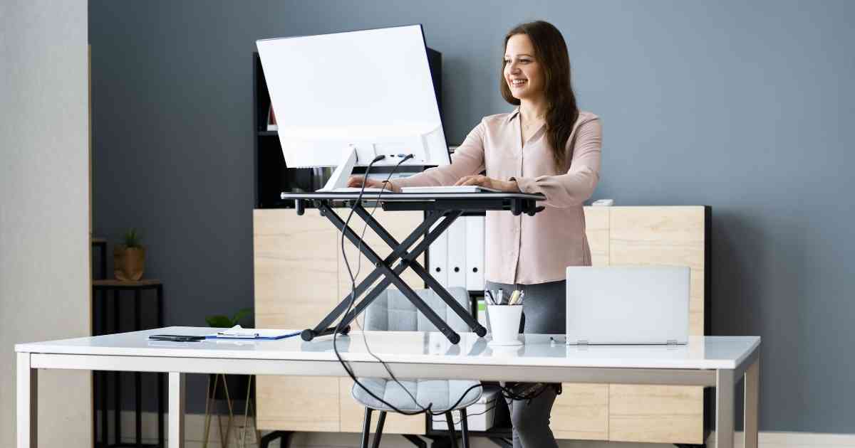 A woman using a standing desk to work on her computer.