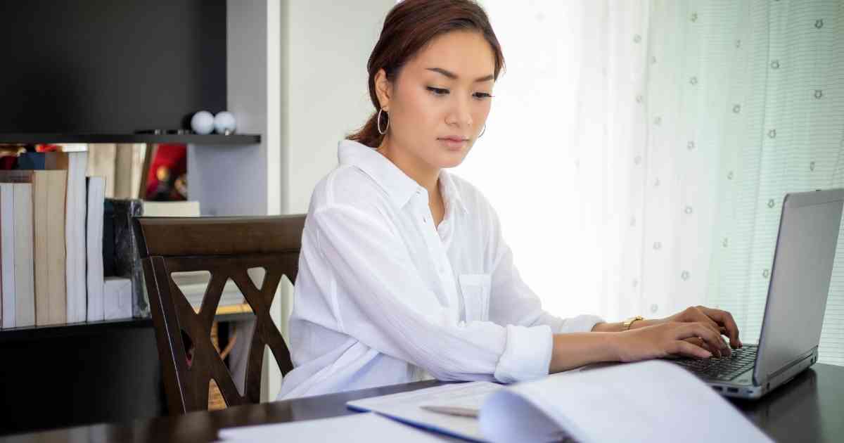 A woman sitting at a desk using a laptop.